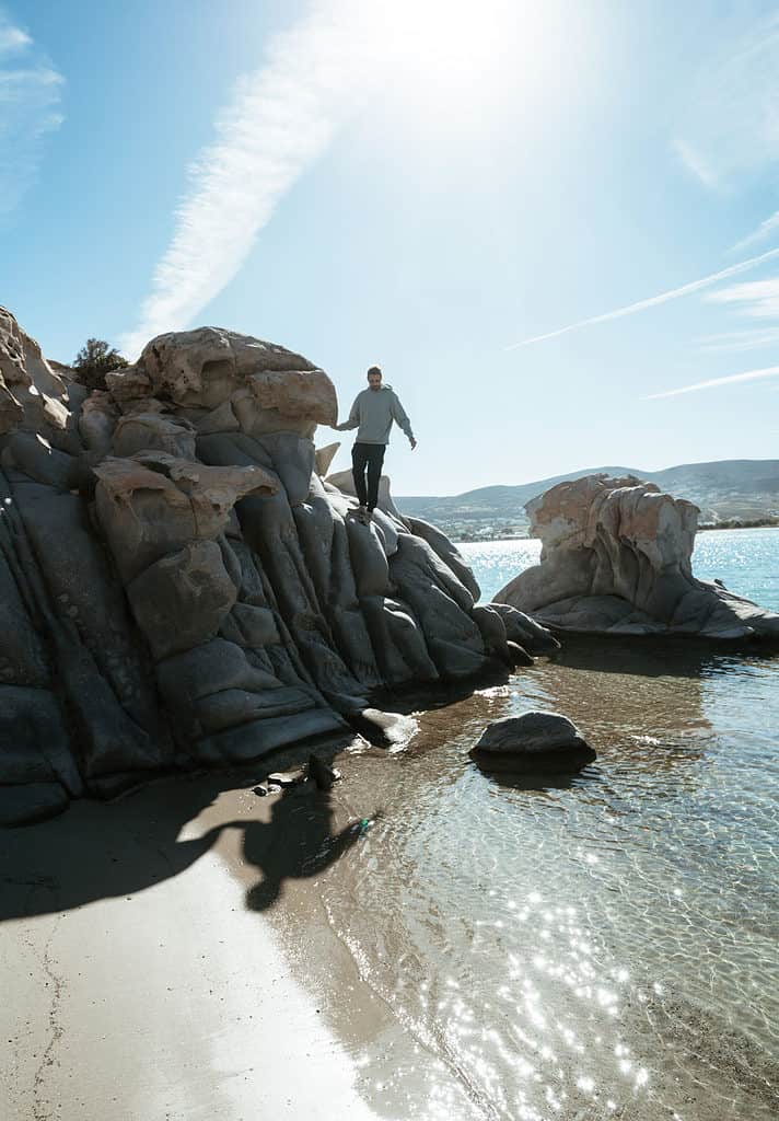climbing rocks at Kolympethres beach in Naoussa, Paros in Greece